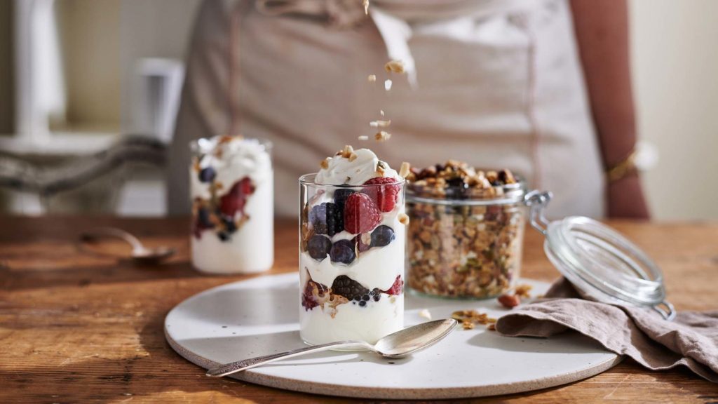 chef adding granola to an organic greek yogurt parfait