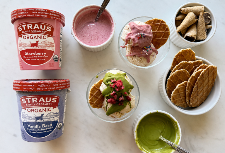 Straus Organic Strawberry and Vanilla Bean ice cream served in glass bowls with homemade magic shell, waffle cookies, and ice cream cones on a marble surface